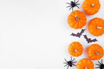 Halloween side border of orange pumpkins with black bats and spiders. Above view over a white...