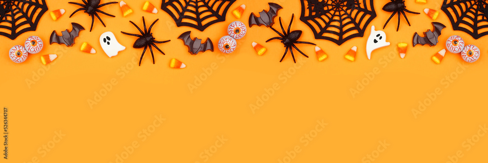 Poster halloween top border of scattered candy and decor. above view over an orange banner background with 