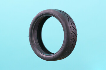 A flying small scooter tire isolated on a blue background. Small. Assistance. Levitate. Driving. Evolution. Front. Quality. Ride. Variation. Repairing. Biking. Energy