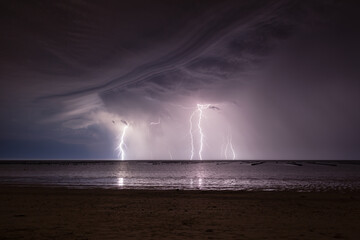 Orage la nuit au-dessus de l'océan avec éclairs multiples éclairant les bouchots de moules et la plage. La Guérinière, île de Noirmoutier