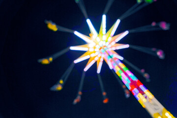 Amusement park ride or carnival rides at night with bright colorful background.