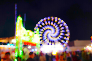 Ferris wheel in an amusement park at night lit up. Blurred colorful fun background.