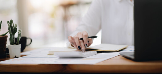 Close up young woman using calculator, managing household monthly budget, summarizing taxes or bills, planning future investments, doing financial affairs at home, accounting bookkeeping concept.