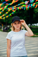 Portrait of a young beautiful girl in the park. A fashionable teenager in casual summer clothes.The girl holds a cap with her hands.
