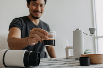 Asian man make and drink his own french press coffee.