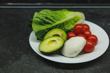 Healthy food at home. Lettuce, tomatoes, avocado, and mozzarella.