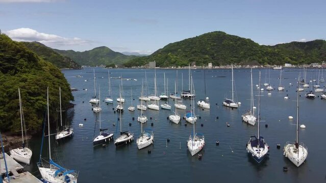 Drone shot of boats on the sea with hills in the background in Numazu, Japan