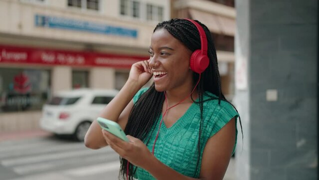 African american woman listening to music dancing at street