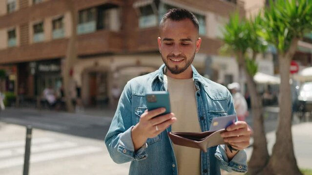 Young hispanic man using smartphone and credit card at street