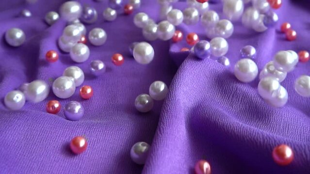 Pearls fall on a blue cloth. Slow motion.