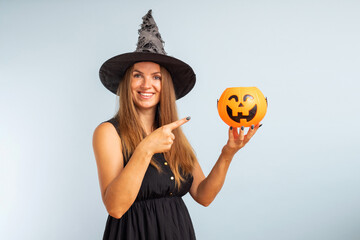 Happy Halloween! Happy young woman in halloween witch costume with pumpkin basket jack-o-lantern