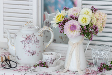 romantisches Arrangement mit Dahlien-Strauß in Weiß und Lila und vintage Porzellan