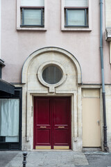 Fototapeta na wymiar Close-up of a vintage red front door of a building in Paris, with a stone arch above