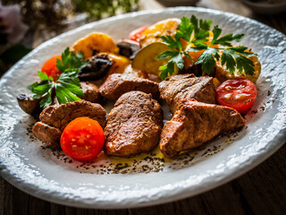 Fried pork loin nuggets with cooked vegetables on wooden table
