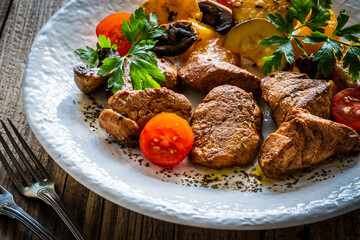 Fried pork loin nuggets with cooked vegetables on wooden table
