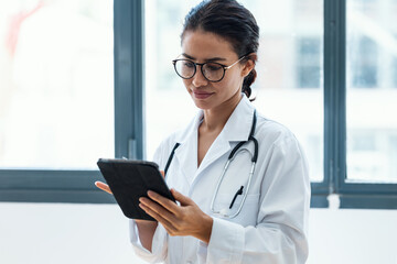 Female doctor using her digital tablet while standing in the consultation.