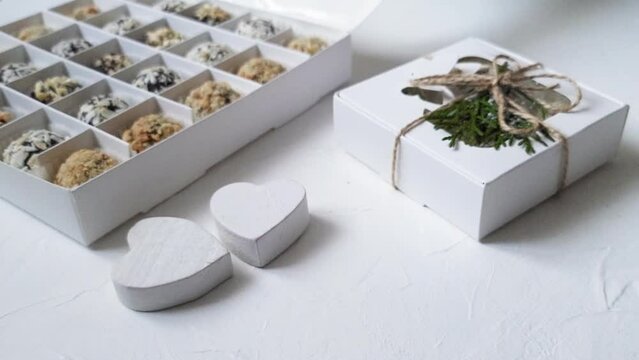 Paper box with chocolates and two wooden white 