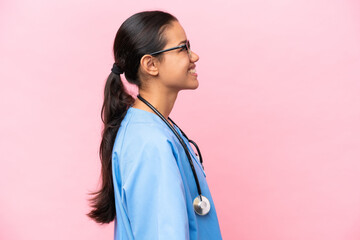 Young nurse Colombian woman isolated on pink background laughing in lateral position