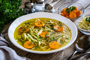 Broth - chicken soup with vegetables on wooden table

