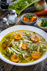 Broth - chicken soup with vegetables on wooden table
