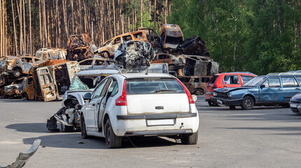Fototapeta premium Shot, damaged cars during the war in Ukraine. The civilian car was damaged. Shrapnel and bullet holes in the car body. Car riddled with bullets. Bullet holes and shell fragments.