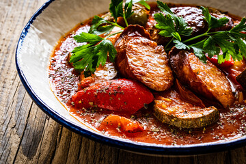 Delicious letcho - vegetables with sausages on wooden table
