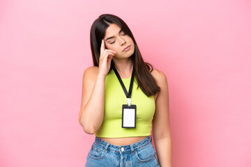 Young Brazilian woman with ID card isolated on pink background with headache