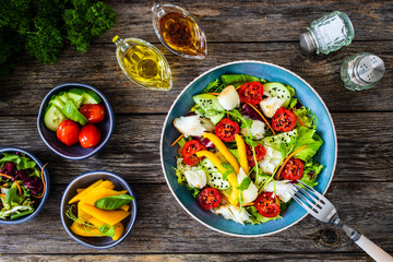 Fish salad - fried halibut fillet with fresh vegetables on wooden table
