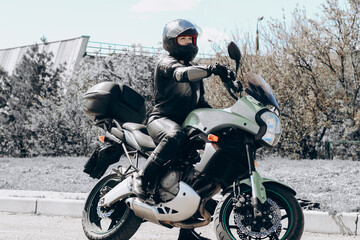 A girl in a protective suit and a black helmet sits on a sports motorcycle.