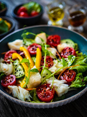 Fish salad - fried halibut fillet with fresh vegetables on wooden table
