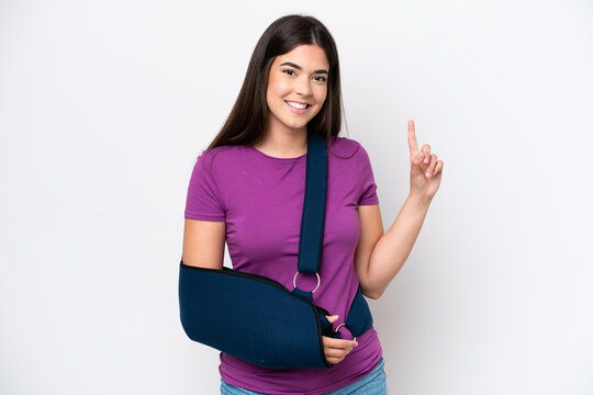 Young Brazilian woman with broken arm and wearing a sling isolated on white background pointing up a great idea