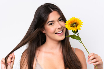 Young Brazilian woman isolated on white background holding a sunflower while smiling. Close up portrait