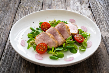 Fried pork loin with fresh vegetables on wooden table
