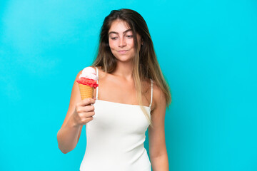 Young woman in swimsuit holding an ice cream isolated on blue background with sad expression