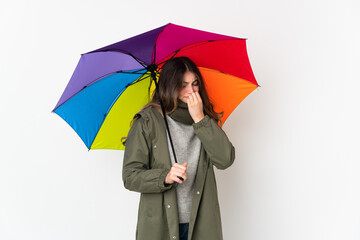 Young caucasian woman holding an umbrella isolated on white background having doubts