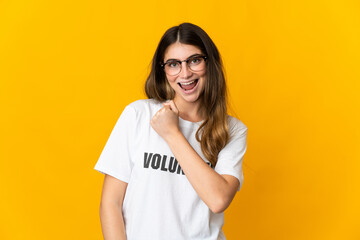 Young volunteer woman isolated on yellow background celebrating a victory