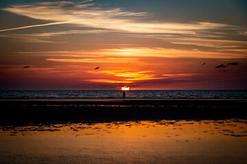 Fototapeta premium Single person in. the distance infront of dramatic colorful sunset