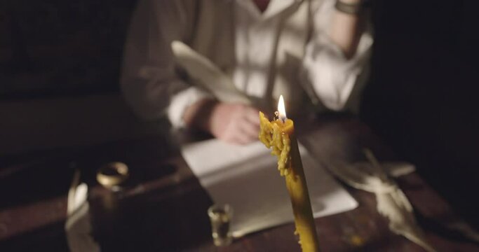 Man Writing Text With A Feather On Paper By Candlelight In Focus, Crane Shot, Close Up.