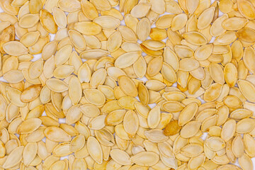 Dried pumpkin seeds in husks. Yellow pumpkin seeds. Wallpaper, background. Flat oval seed of squash. Edible seed of a pumpkin. Healthy food. Natural product. Roasted snack. Pepita. Top view. Close-up