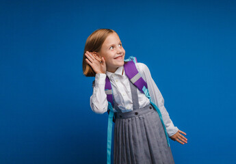 Portrait of a teenage girl holding her hand to her ear and listening to something, isolated on a...