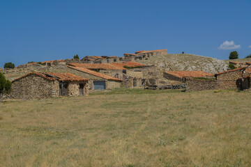 Aldea agrícola semi abandonada en tierras de Teruel, Aragón, antiguas edificaciones de piedra para ganado y útiles de campo de siega y recolección