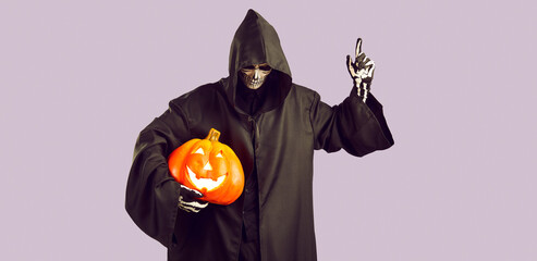 Man in image of mystical creepy grim reaper with pumpkin in his hand raises finger in warning with...