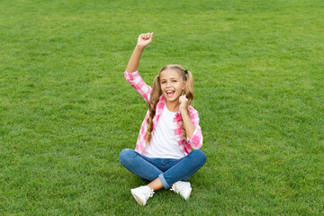 happy teen child sit on green grass outdoor. happiness