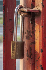Old worn padlock locked on the paint-shabby gate. Metaphor of a liquidated business. Soft focus view. - 526379557
