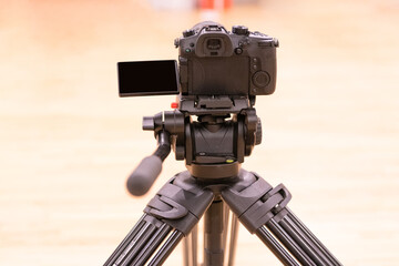 Modern digital camcorder camera with microphone standing on tripod
