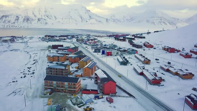 Aerial view of Longyearbyen, Svalbard in winter. With colorful houses, snow-capped mountains, with avalanche protection and fjord. Drone flight. High quality 4k footage