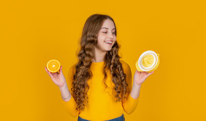 cheerful teen girl hold orange and juicer on yellow background