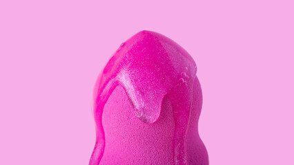 Closeup photography of beauty blender with dripping cosmetic gel on it.Neutral pink background.