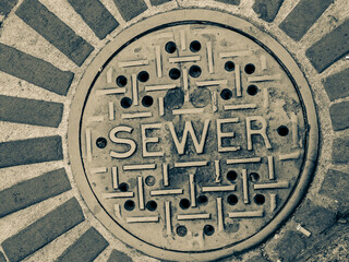 Fototapeta na wymiar Grimy sewer manhole cover in city street