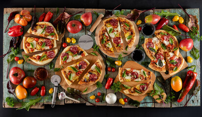 Five cutted tomatoes pizzas flat lay with tomato and fresh greens on shabby background